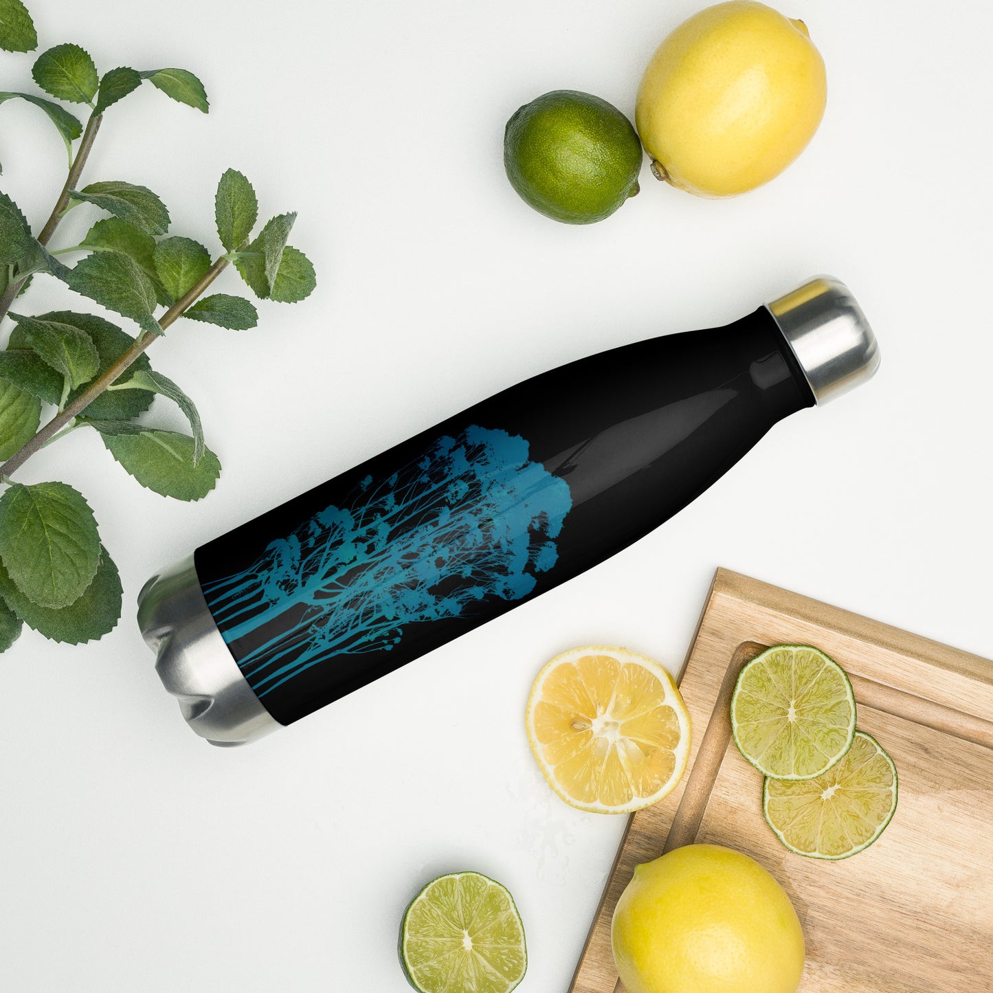 Delicate Trees by Michelle Penland Dodson Stainless steel insulated water bottle laying on a counter with some lemons and limes nearby to show scale.