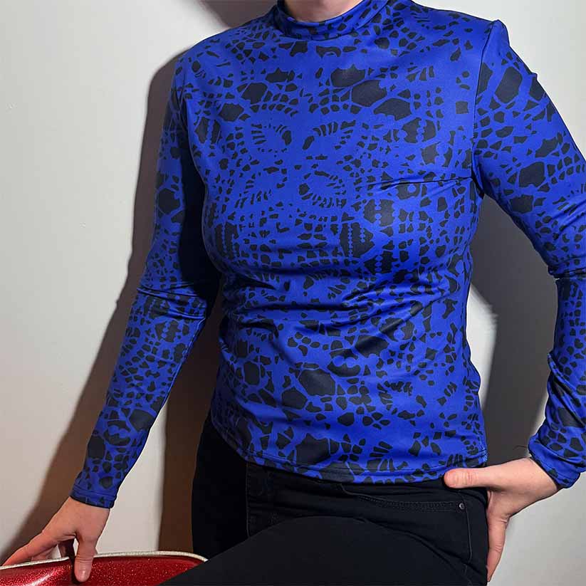 Person wearing blue and black long-sleeve shirt with lace pattern on a white background