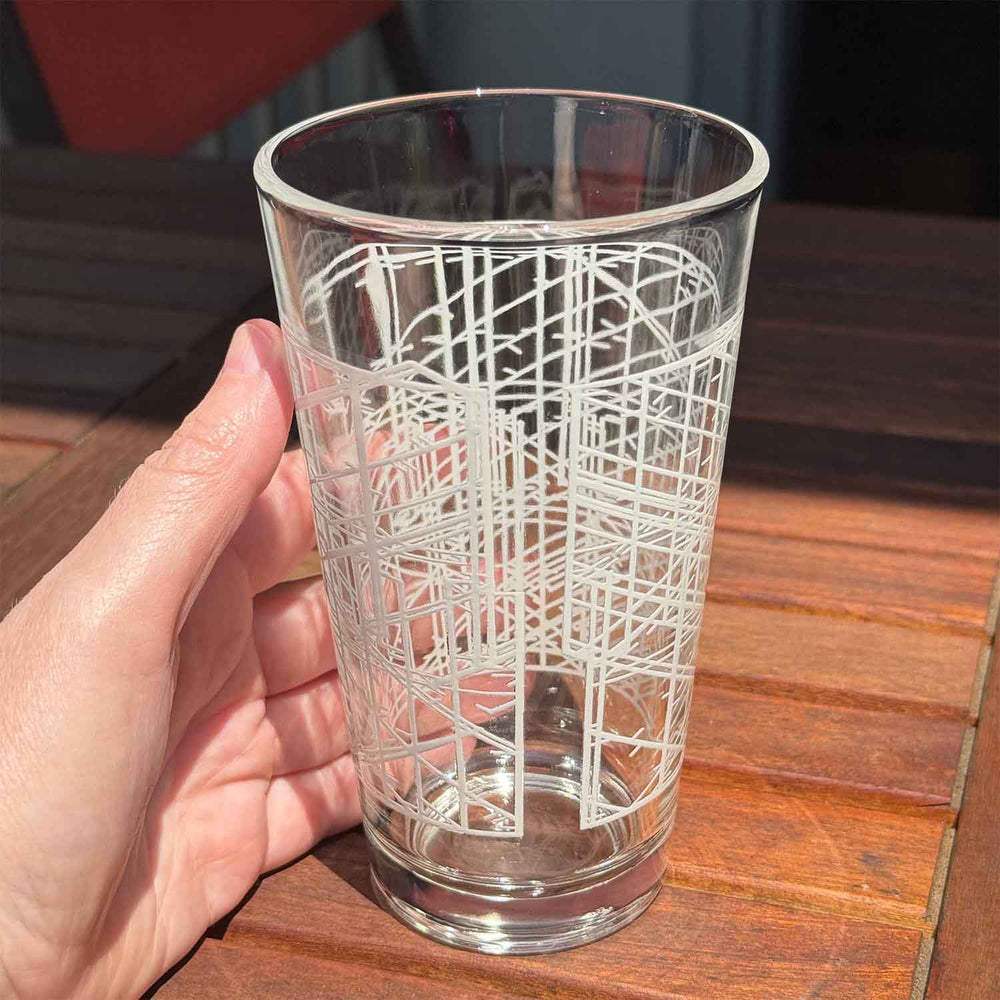 Clear glass with geometric pattern held by a hand on a wooden surface