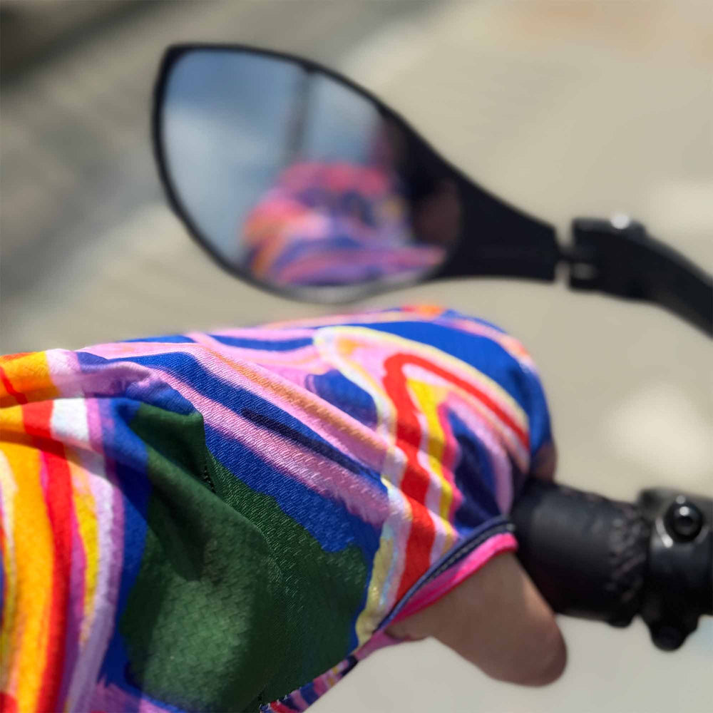 Thumb holes detail of hand holding handlebars of bike wearing colorful psychedelic abstract patterned sun protection hoodie