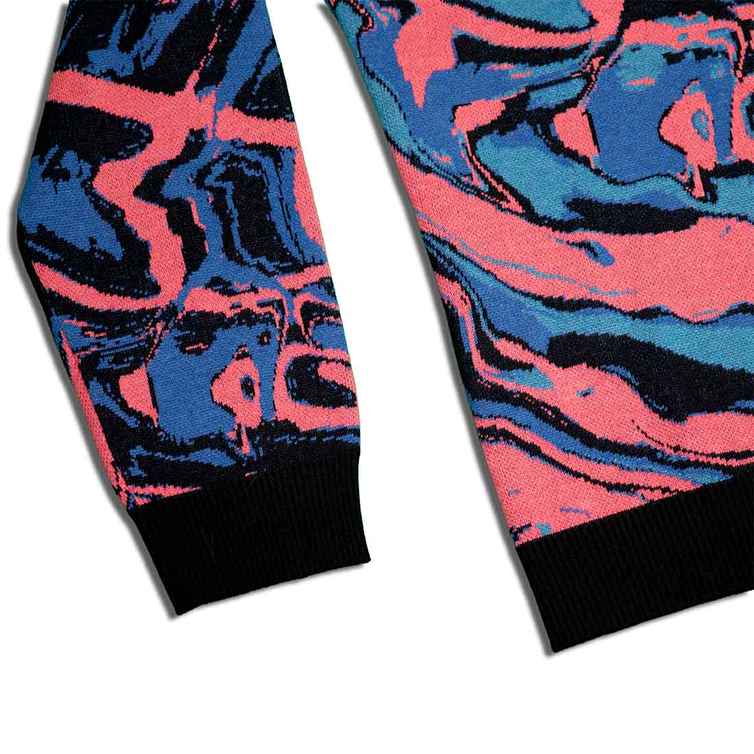 Sleeve detail of colorful knitted sweater with abstract design in pink, blue, and black on a white background